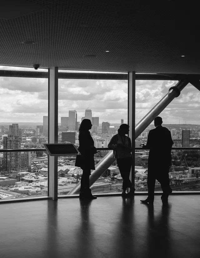 Tre colleghi alla vetrata di un ufficio con vista sullo skyline